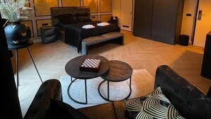 A modern hotel room with a large bed, a sofa, two small tables, and a decorative vase. - Hotel 83 (Amsterdam)