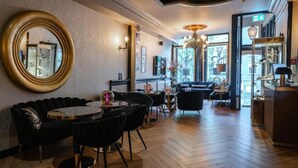 A modern interior with a round mirror, black sofas, a round table, and a bar area. - Hotel 83 (Amsterdam)