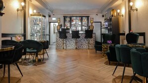 A bar area with a mirrored wall, bar stools, and a counter with a glass display. - Hotel 83 (Amsterdam)