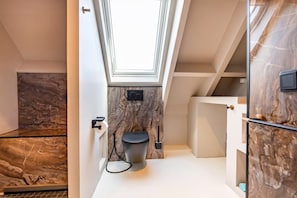 Ein modernes Badezimmer mit Dachfenster, Marmorwänden und Toilette.