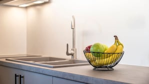 Una cucina con una ciotola di metallo contenente banane e mele sul piano di lavoro.