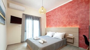 Una camera da letto moderna con un letto, comodini, una TV e una parete decorata a rosso.