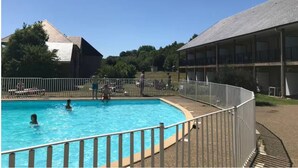 A swimming pool with a metal fence, surrounded by buildings with a flat roof and a covered area with a balcony. - Modern studio with terrace 5 min from Honfleur parking and swimming pool (Équemauville)