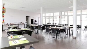 A spacious cafeteria with multiple tables and chairs, large windows, and a central service area with a coffee machine. - Modern studio with terrace 5 min from Honfleur parking and swimming pool (Équemauville)