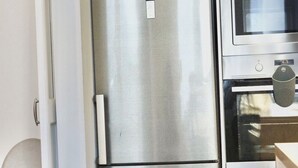 A stainless steel refrigerator with a digital display, a microwave, and a small kitchen counter. - Spacious 3-bedroom apartment in the heart of Brussels for 8 people (Bruxelles)