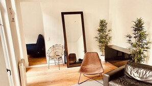 A modern living room with a round coffee table, a sofa, a chair, and a large mirror. - Spacious 3-bedroom apartment in the heart of Brussels for 8 people (Bruxelles)