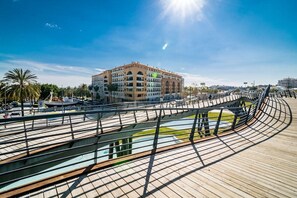 En moderne bygning med et flerlagsdesign, en buet bro og en kajepromenade.