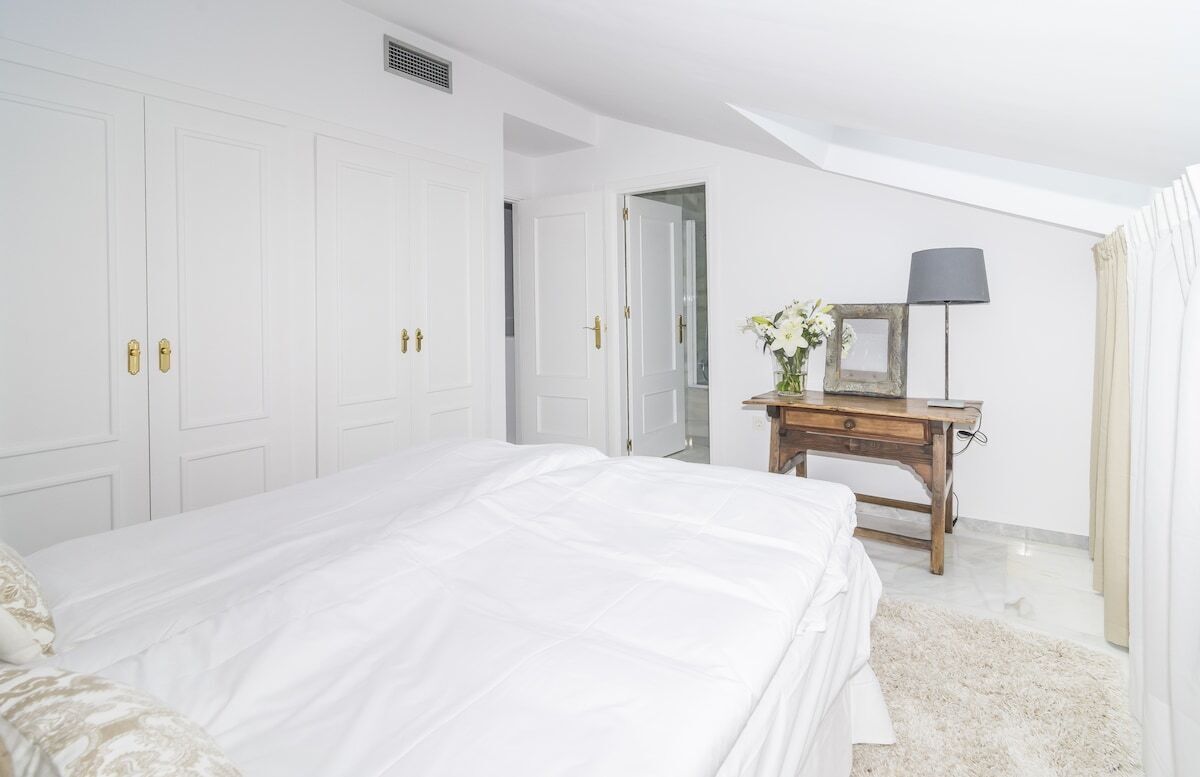 Ein Schlafzimmer mit einem großen Bett, einem Nachttisch aus Holz, einem Spiegel und einer Lampe.