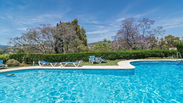 A swimming pool with clear blue water, surrounded by lounge chairs and a well-maintained hedge. - Ap128 - Big Townhouse - Sunny Side of Aloha Pueblo (Marbella)