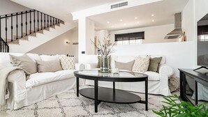 A modern living room with a staircase, two white sofas, a round coffee table, and a TV on a stand. - Ap128 - Big Townhouse - Sunny Side of Aloha Pueblo (Marbella)