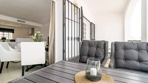 A modern living room with a dark wooden table, two grey upholstered chairs, a white sofa, and a decorative glass candle holder. - Ap128 - Big Townhouse - Sunny Side of Aloha Pueblo (Marbella)