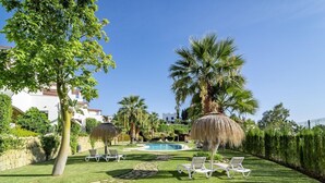 A pool area with lounge chairs, palm trees, and a clear blue sky. - Ar23 - Holiday Flat, Puerto Banus by Roomservices (Marbella)
