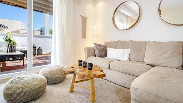 A living room with a sofa, round mirrors, a wooden coffee table, and a view of the outside. - Ar23 - Holiday Flat, Puerto Banus by Roomservices (Marbella)