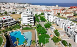 Zona residencial com edifícios modernos, piscina e vista para o mar.