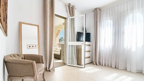 A modern hotel room with a large sliding glass door leading to a balcony, a comfortable armchair, a flat-screen TV, and a minimalist decor style. - Cpg- Perfect Holiday Home Close to Puerto Banus (Marbella)