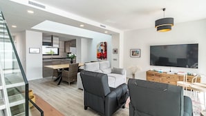 A modern living space with a staircase, a dining area, a sofa, and a TV. - Lmt46 - Modern Style Spacious Townhouse (Estepona)