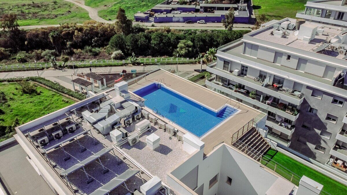 Ein Pool auf dem Dach mit klarem, blauem Wasser, umgeben von Klimaanlagen und einer kleinen Liegefläche.
