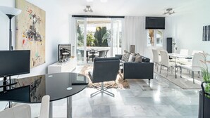 Una sala moderna con una mesa de comedor de cristal, sofás blancos y negros, y un cuadro abstracto grande en la pared.