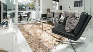 Una sala de estar moderna con una mesa de centro de vidrio, un sofá de cuero negro y una alfombra estampada.
