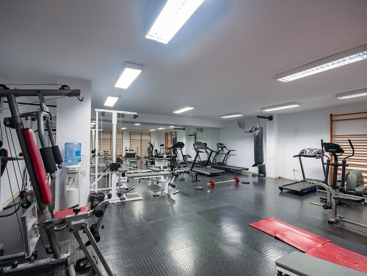 A gym with various exercise equipment, a water dispenser, and a large mirror.