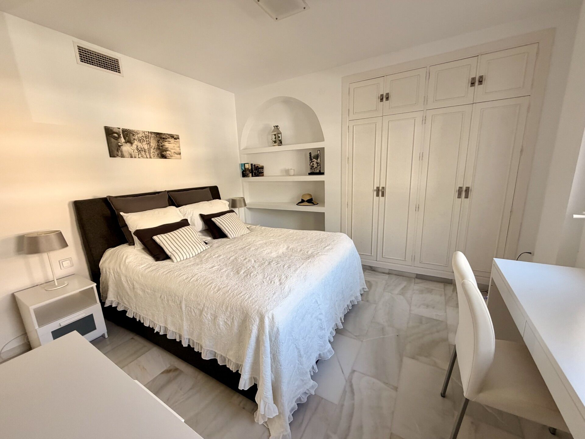 A bedroom with a bed, bedside tables, a desk, and a wardrobe.