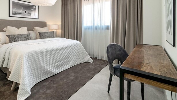 A modern hotel room with a large bed, a wooden desk, and a view of the outdoors through sheer curtains. - Inf27e- Holiday Home Estepona by Roomservices (Estepona)
