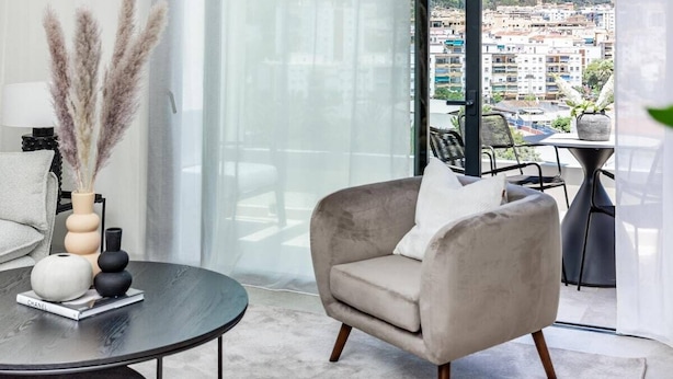 Ein modernes Wohnzimmer mit Blick auf eine Stadtlandschaft durch große Fenster.