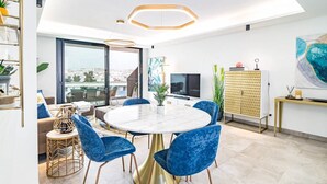 Uma sala de jantar moderna com uma mesa redonda, cadeiras de veludo azul e base dourada.