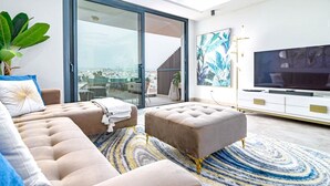 Uma sala de estar moderna com sofá, pufê e uma televisão de tela plana.