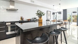 A modern kitchen with a large island, bar stools, and a view of the dining area. - LVB - Casa Linda Vista by Roomservices (Marbella)