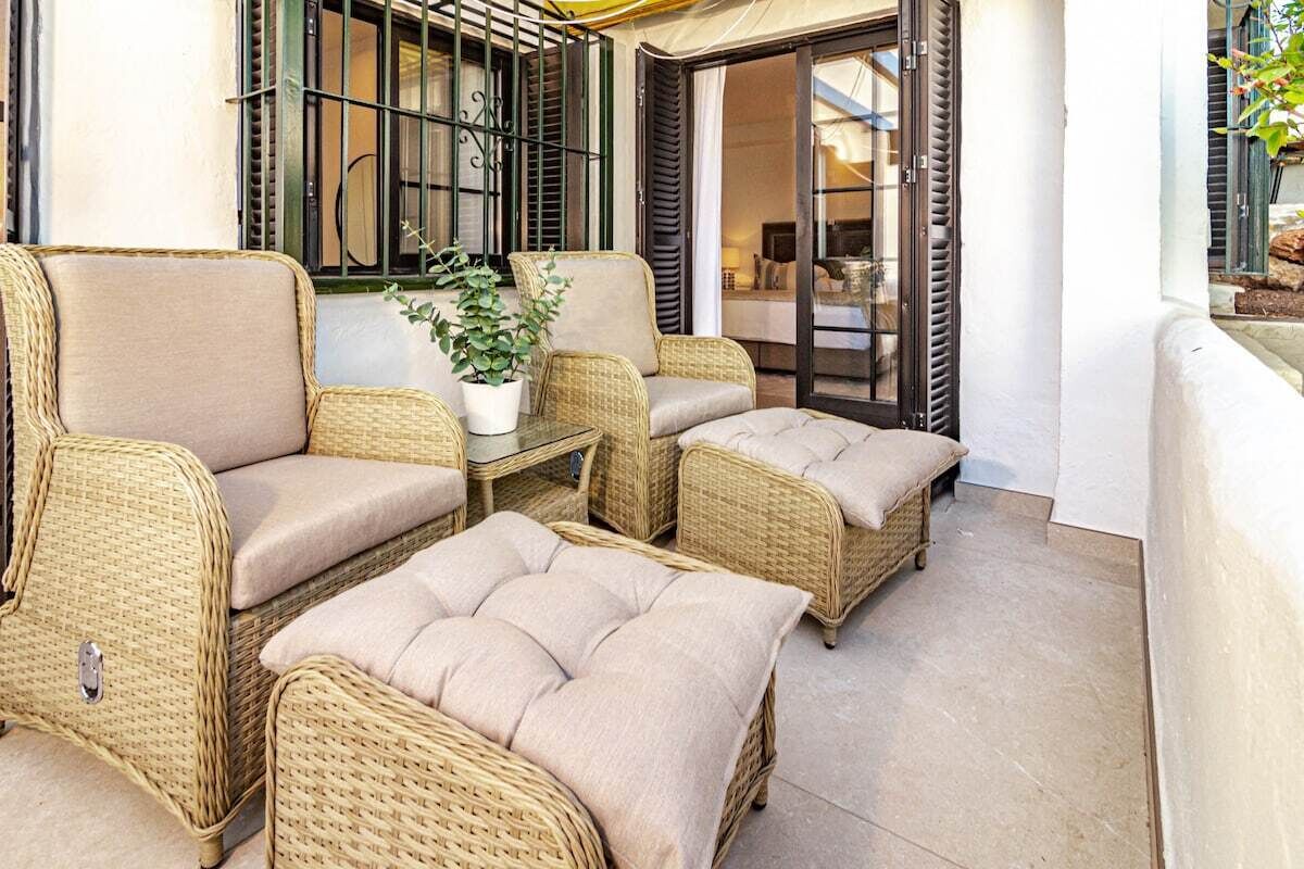 A patio area with wicker furniture and a potted plant.