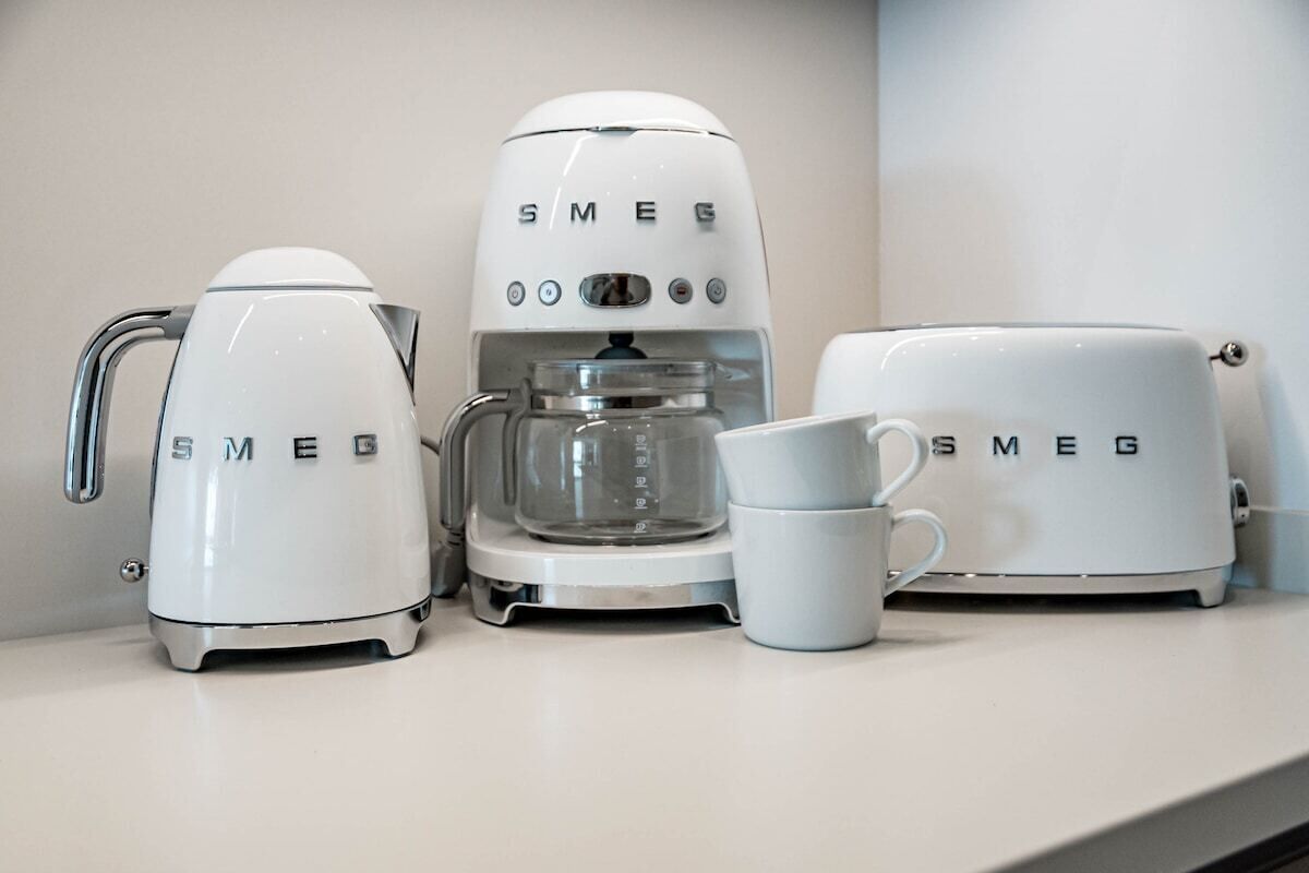 A kitchen with a coffee maker, a coffee pot, and a coffee grinder.
