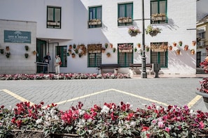 A building with a sign indicating it is a permanent educational institution, outdoor seating, and flower beds. - A2- Seaclub Suites by Roomservices (Estepona)