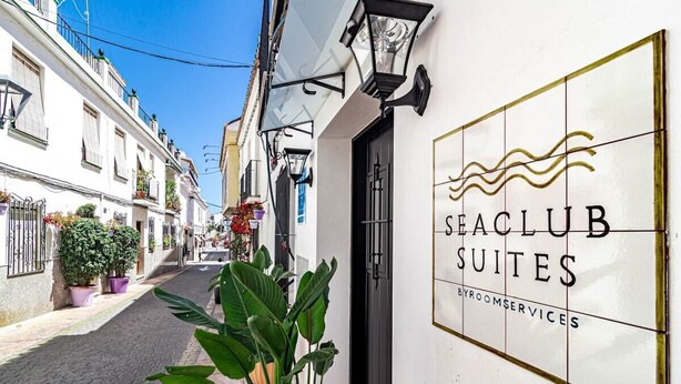 Un vicolo stretto con un edificio con la scritta "SEACLUB SUITES BYROOMSERVICES".