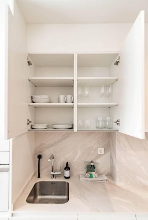 A kitchen with a built-in sink, white cabinets, and marble backsplash. - A2- Seaclub Suites by Roomservices (Estepona)