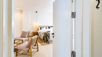 A hotel room with a bed, two chairs, a nightstand, and a hanging light fixture.