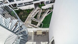 A modern building with a spiral staircase, outdoor seating area, and a small garden. - Eg54a - Luxury Penthouse With Private sun Terrace (Estepona)