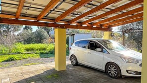 Een overdekte parkeerplaats met een witte auto onder een houten balkenconstructie.