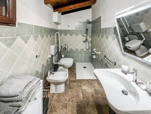 Ein Badezimmer mit zwei Toiletten, einem Waschbecken, einer Dusche und einem Spiegel.