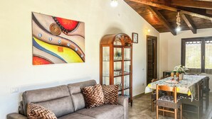 Een woonkamer met een bank, een eettafel en een decoratief schilderij.