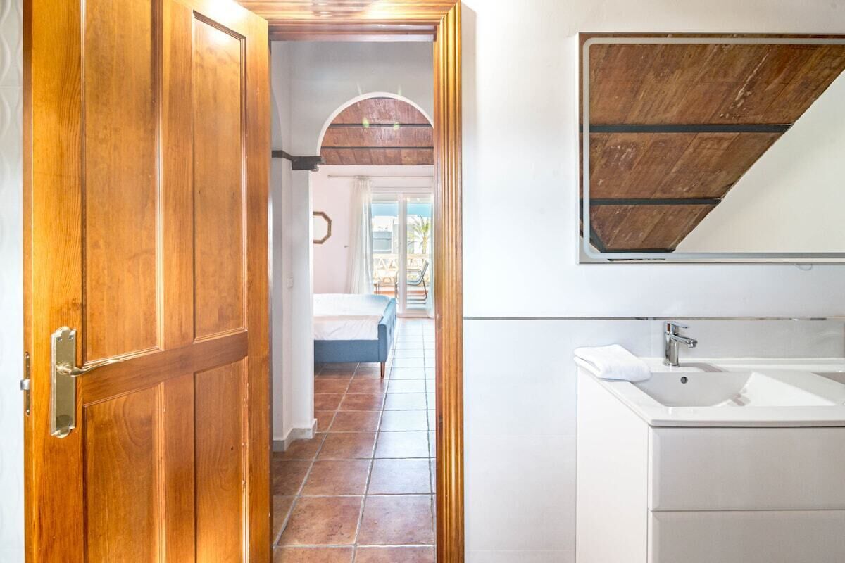 Une porte en bois qui donne sur une chambre à coucher, avec un lit et une vue sur l’extérieur.