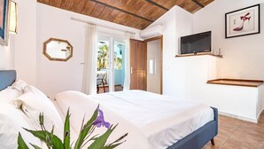 A bedroom with a bed, a TV mounted on the wall, and a door leading to a balcony. - PG9 - Andalucian 3-story Townhouse Near Estepona (Estepona)