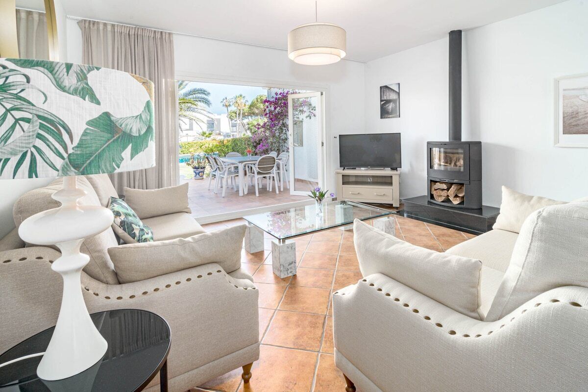 A modern living room with a sofa, coffee table, TV, and fireplace.
