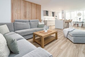 A modern living room with a grey sofa, a wooden coffee table, and a dining area with a glass table and chairs. - Eac3f- Modern & Light Apartment Steps From the sea (Estepona)