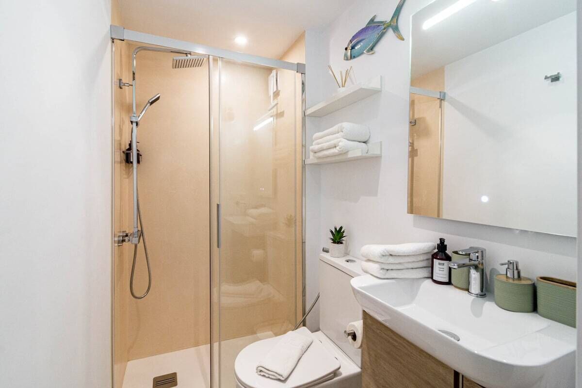 A modern bathroom with a glass-enclosed shower, a white sink, and a large mirror.