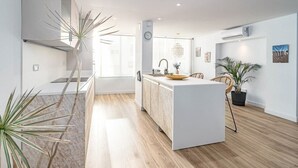 A modern kitchen with a central island, wooden flooring, and potted plants. - Eac3f- Modern & Light Apartment Steps From the sea (Estepona)