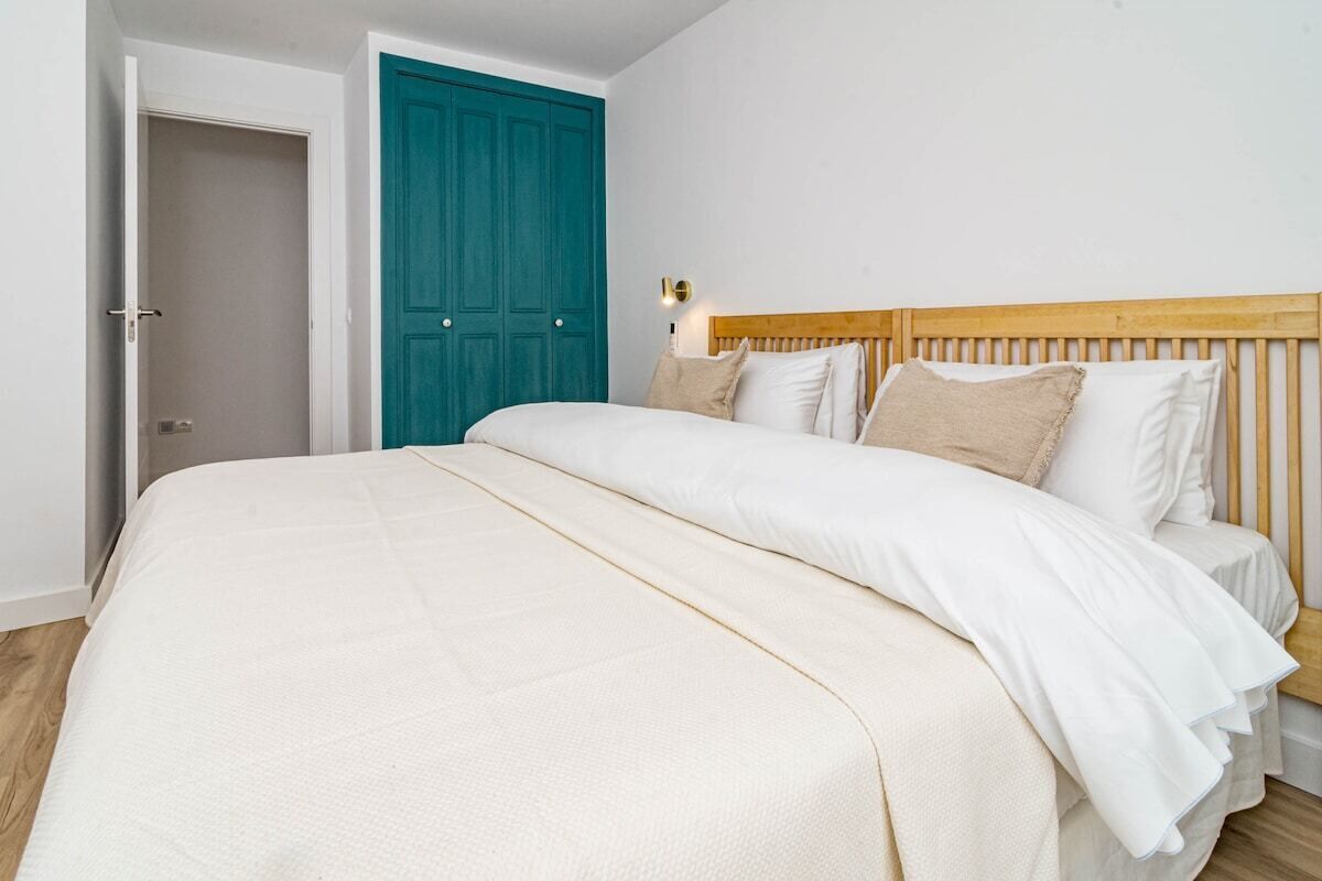 Een slaapkamer met een bed, een blauwgroene deur en een houten hoofdbord.