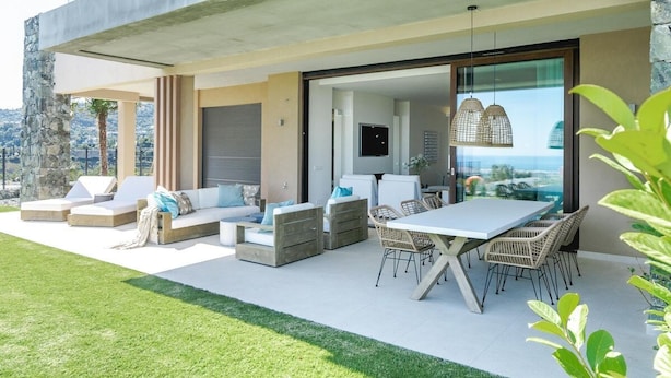 Un espacio al aire libre con mesa de comedor, sillas, sofás y televisor.
