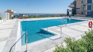 Una piscina en la azotea con agua cristalina y vistas a edificios modernos y al océano.
