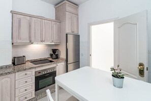Una cocina equipada con horno, cafetera y refrigerador.